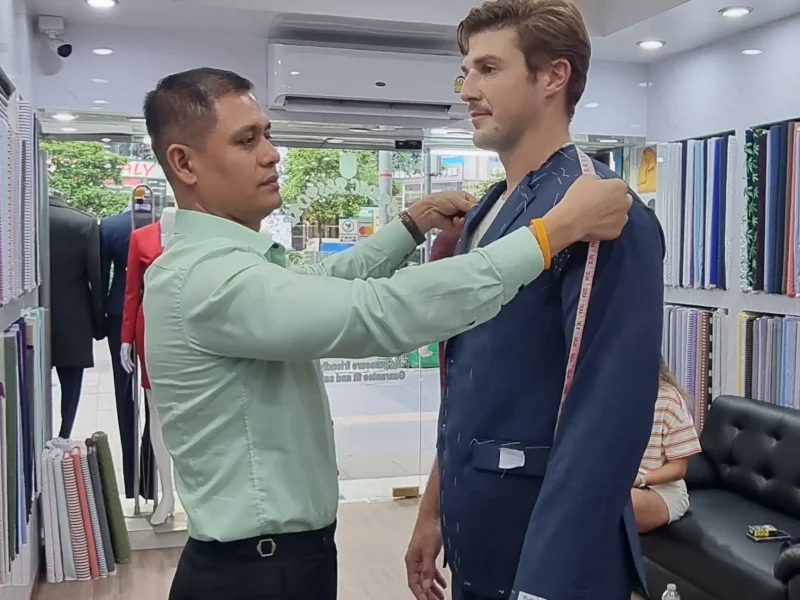 Bespoke fitting session with tailor adjusting suit jacket on male client